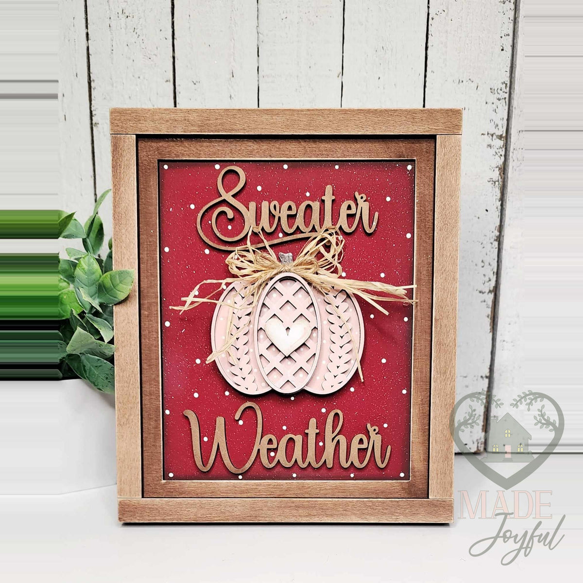 Sweater Weather 3D wood insert with a blush sweater-knit pumpkin, raffia bow, and script lettering on a deep red polka-dot background, in a stained farmhouse frame.