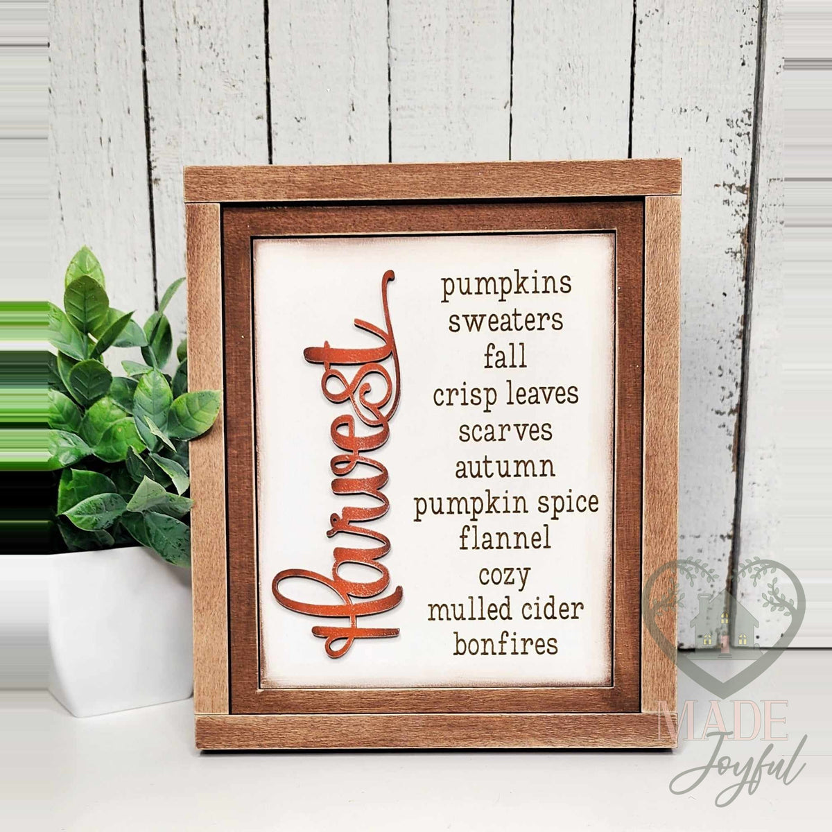 Harvest word-list insert with pumpkins, sweaters, fall, crisp leaves, scarves, autumn, pumpkin spice, flannel, cozy, mulled cider, and bonfires, in a stained farmhouse frame.