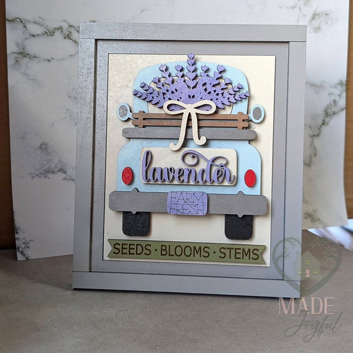 Vintage blue farm truck 3D wood insert carrying a lavender bundle with a Lavender plate and a Seeds, Blooms, Stems banner, in a gray farmhouse frame.