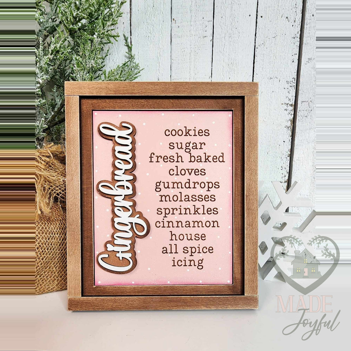 Gingerbread word-list insert with cookies, sugar, fresh baked, gumdrops, molasses, sprinkles, cinnamon, and icing on a pink background in a stained farmhouse frame.