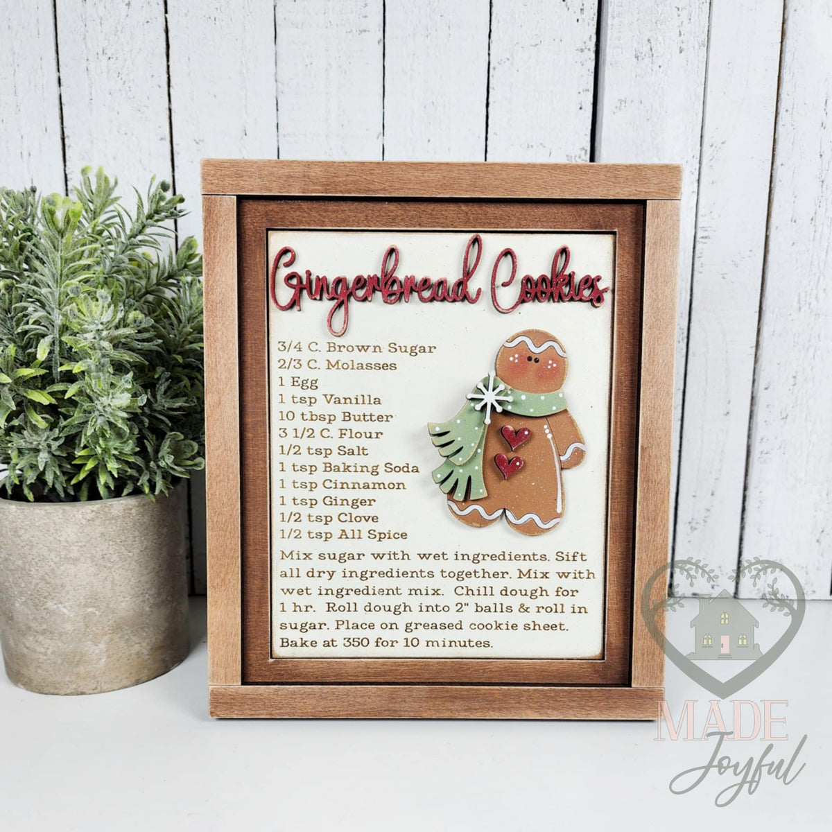 Gingerbread Cookies recipe card 3D wood insert with red script title and a small gingerbread man in a green scarf, in a stained farmhouse frame.