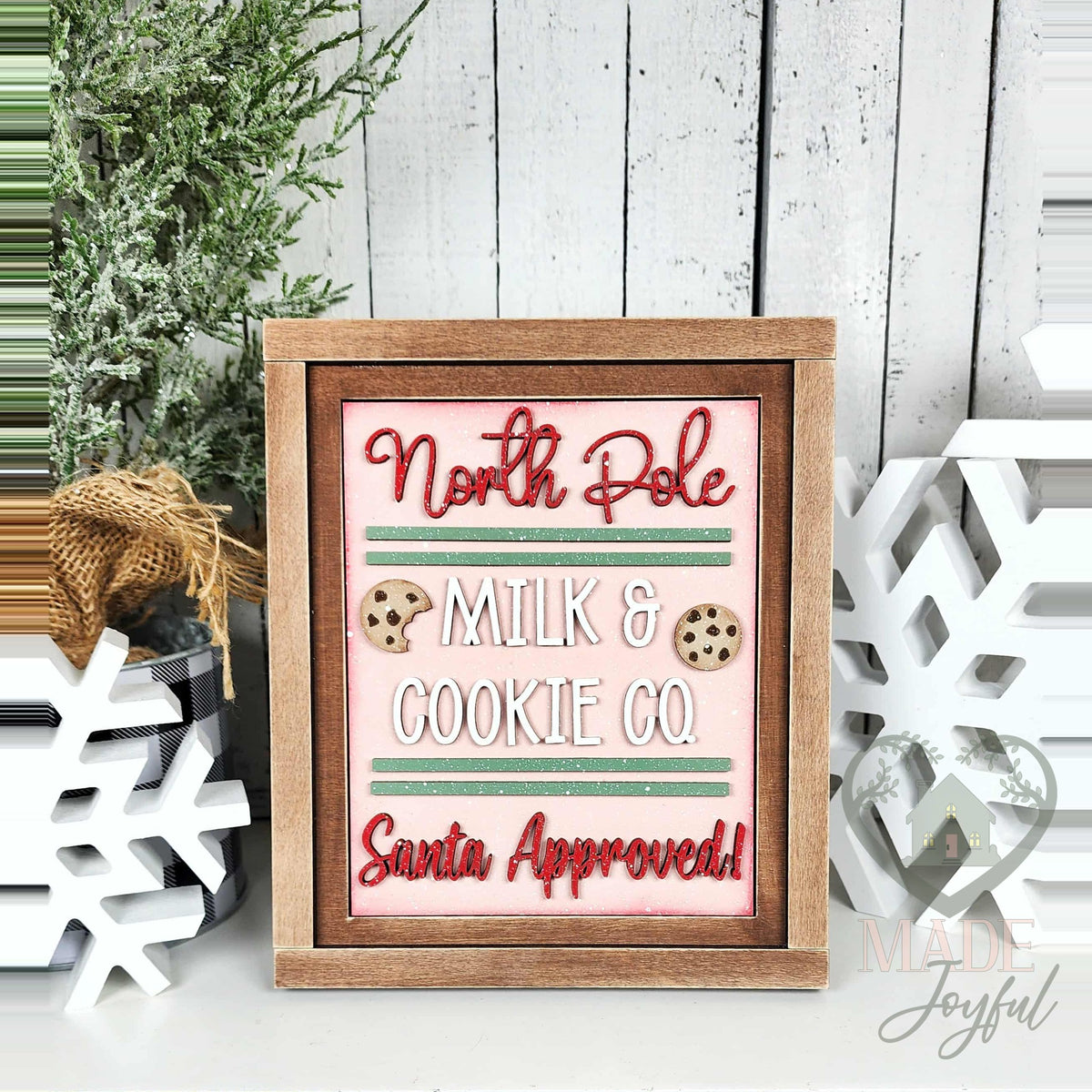 North Pole Milk & Cookie Co. Santa Approved 3D wood insert with red script, green stripes, and chocolate chip cookies on pink, in a stained farmhouse frame.