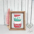 Stack of retro mixing bowls in red, mint, and pink with trees and Jolly script, 3D wood insert in a stained farmhouse frame beside a pink bottle-brush tree.