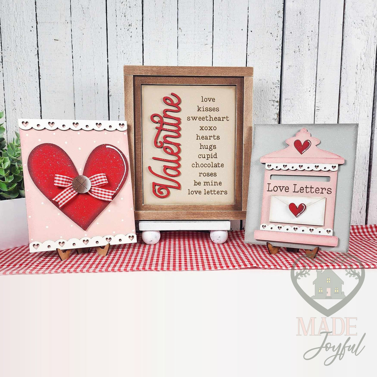 Valentine insert trio of hand-painted 3D wood signs: a Valentine word list in a stained frame with a red gingham-bow heart and a Love Letters mailbox on stands, made in Brentwood, TN.