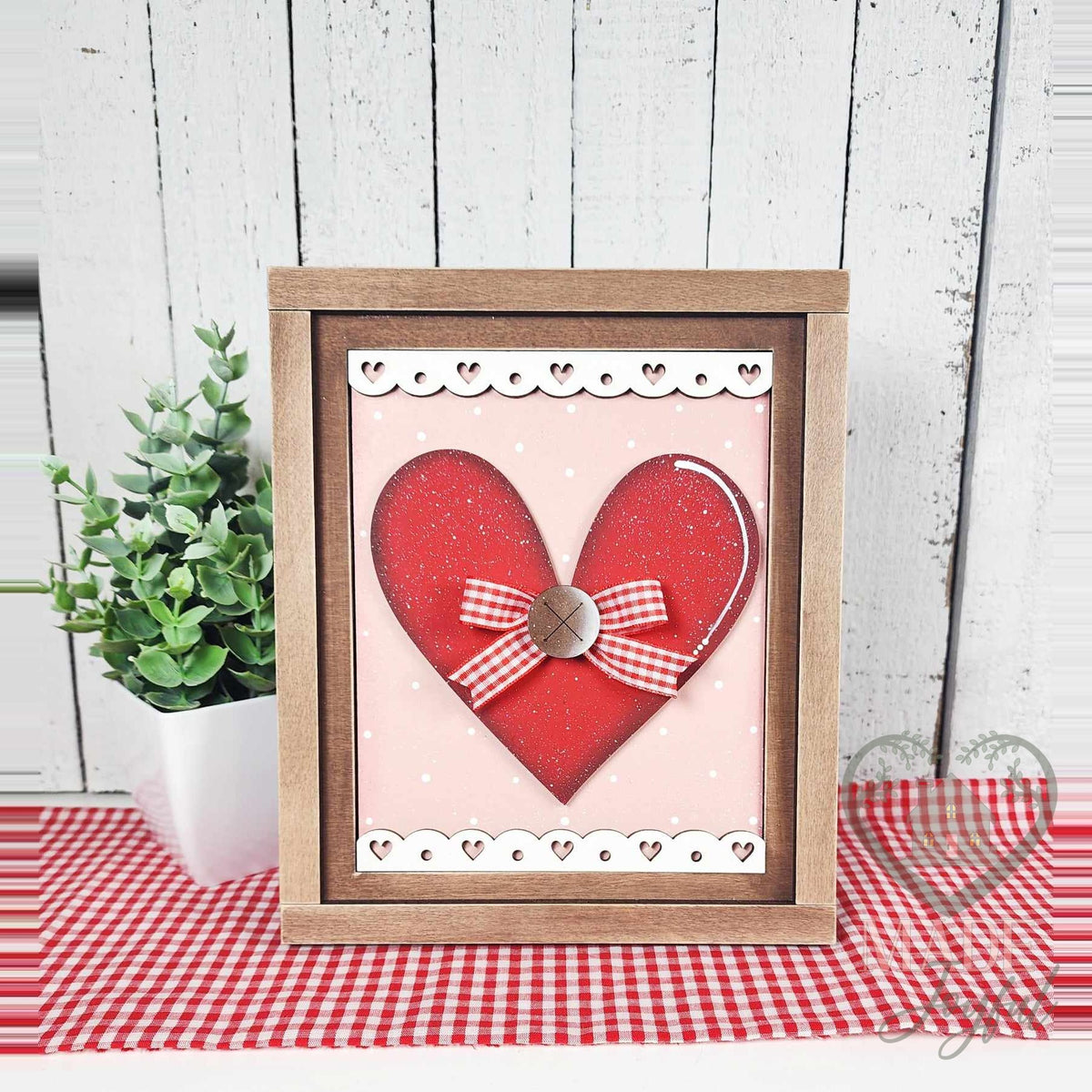 Big red heart 3D wood insert with a gingham bow and button on pink polka dots with white heart-lace borders, in a stained farmhouse frame.