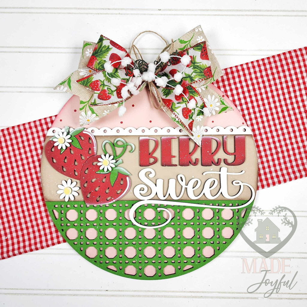 Berry Sweet round wood door hanger with red strawberries, white daisies, and a green polka-dot basket band, topped with a strawberry print bow, hand-painted in Brentwood, TN.