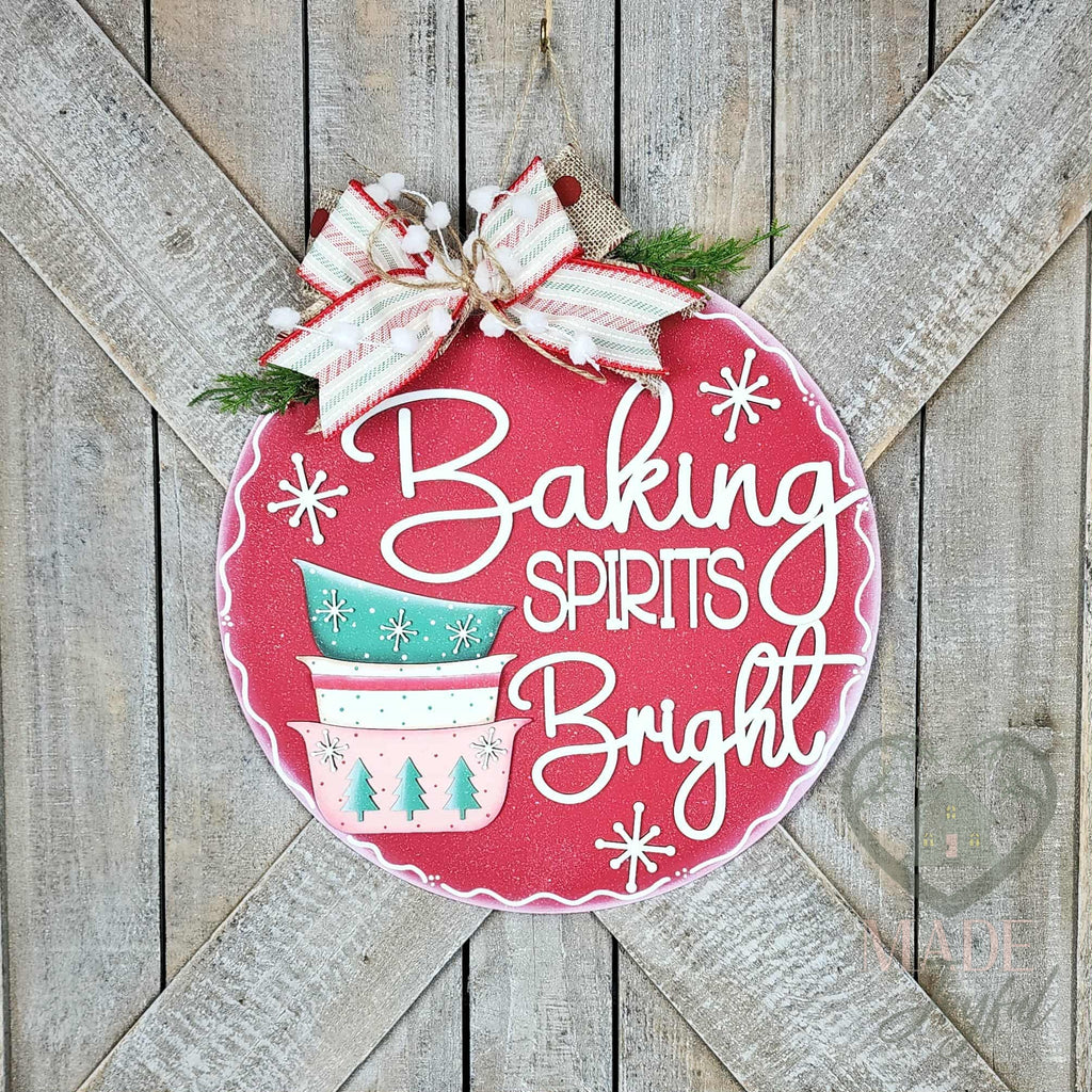 Baking Spirits Bright round wood door hanger with stacked mint and pink mixing bowls on red with white script and a candy-stripe bow, hand-painted in Brentwood, TN.