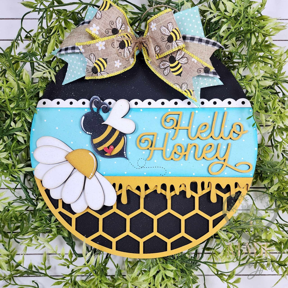Hello Honey round wood door hanger with a bumble bee, white daisy, turquoise band, and black honeycomb with dripping honey, topped with a bee print bow, hand-painted in Brentwood, TN.