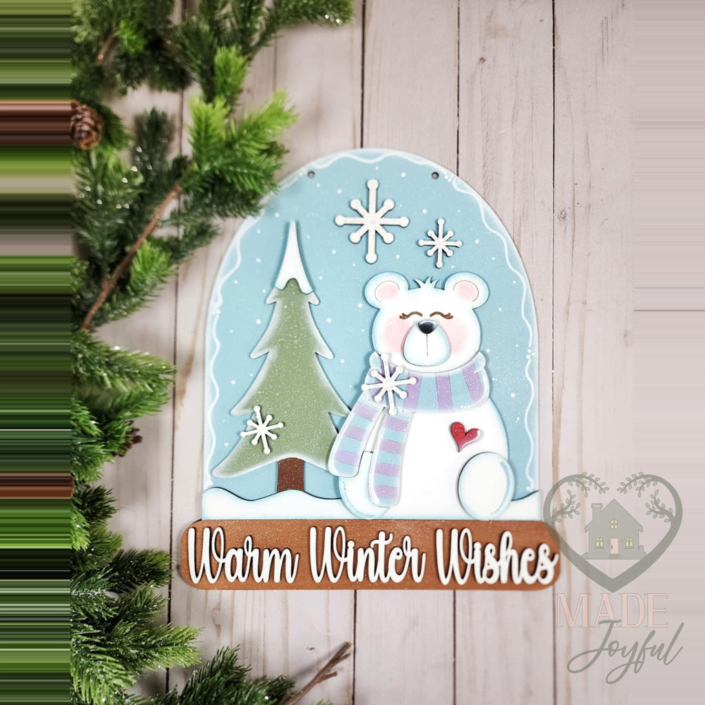 Warm Winter Wishes snow globe door hanger with a polar bear in a lavender scarf, a snowy tree, and a wood banner, hand-painted in Brentwood, TN.