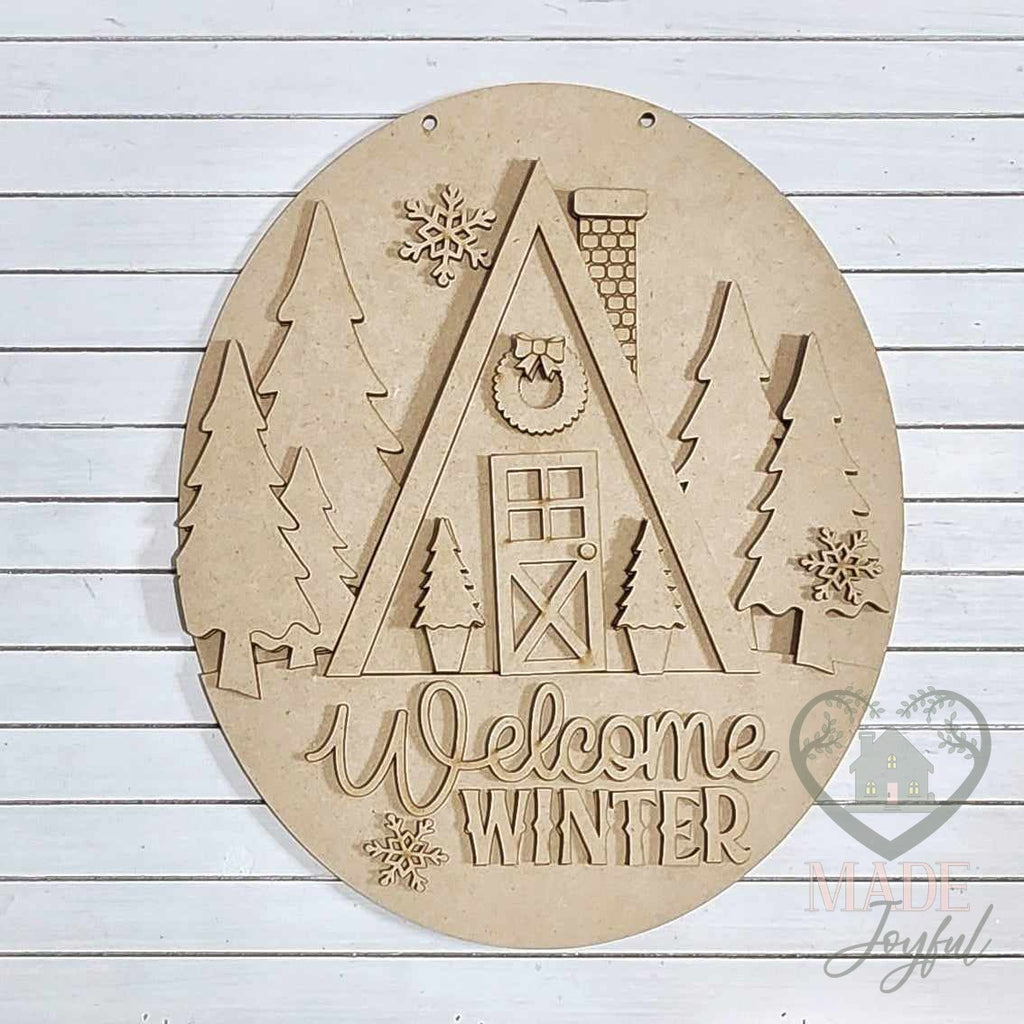 Unfinished laser-cut wood Welcome Winter Cabin door hanger kit, ready to paint at a DIY party in Williamson County, TN.