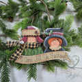Christmas caroler ornament with two singers in a bonnet and top hat above an O Come All Ye Faithful banner, with plaid fabric, hand-painted in Brentwood, TN.