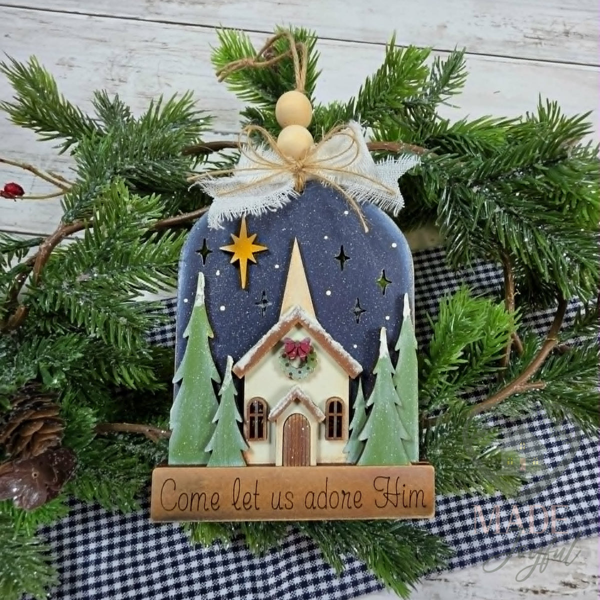 Christmas church ornament with a white chapel, evergreen trees and a gold star on navy, with a Come Let Us Adore Him banner, hand-painted in Brentwood, TN.