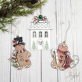 Victorian gingerbread ornament set with a white gingerbread house and two gingerbread men in scarves and a top hat, hand-painted in Brentwood, TN.