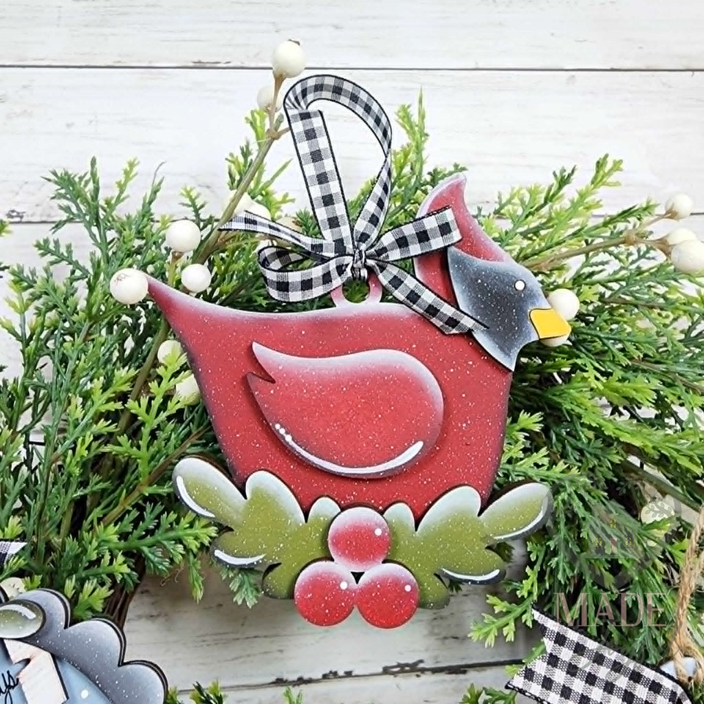 Red cardinal ornament perched on holly and berries with a black and white gingham bow, hand-painted in Brentwood, TN.