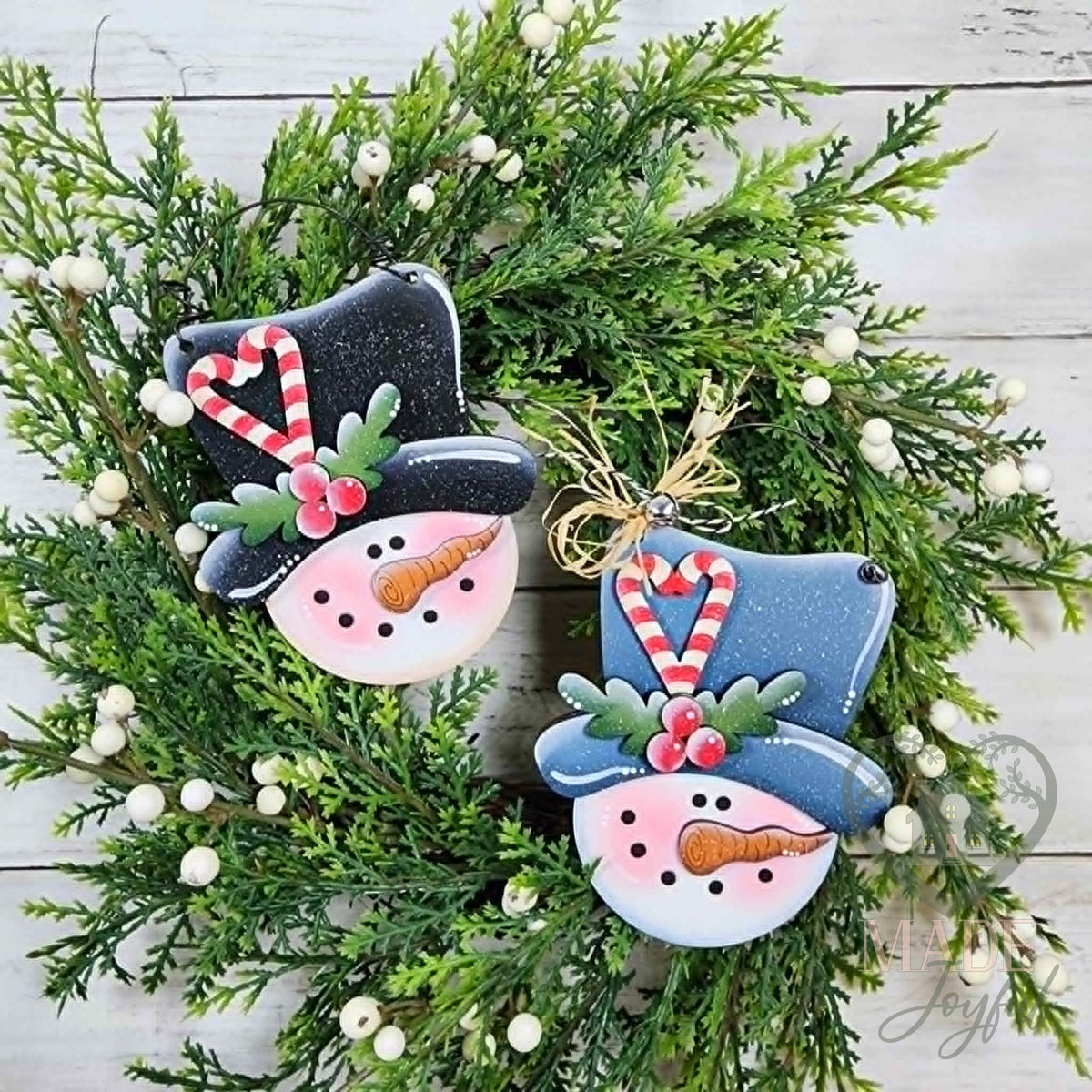 Two pop-out snowman face ornaments with candy cane hats and carrot noses, hand-painted in Brentwood, TN.