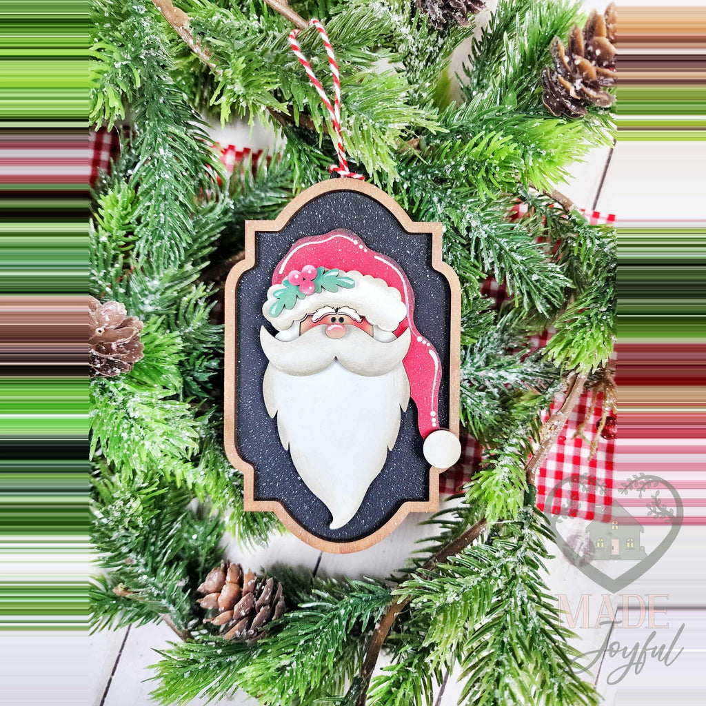 Santa portrait ornament with a pink hat and white beard on a black label frame, hand-painted in Brentwood, TN.