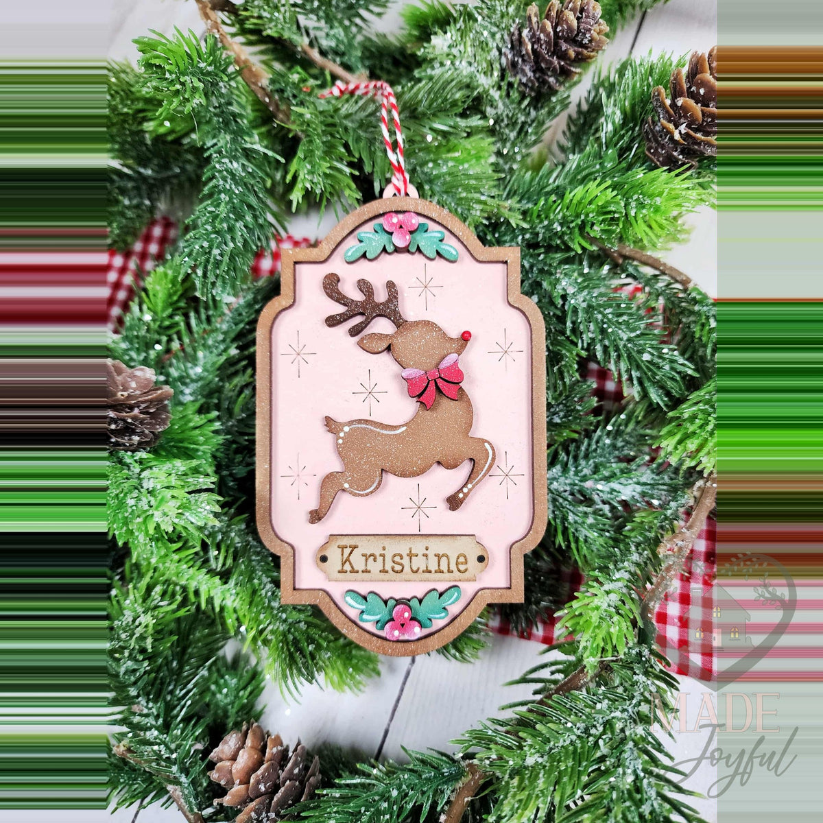 Personalized reindeer ornament with a prancing reindeer and name plate on pink, hand-painted in Brentwood, TN.