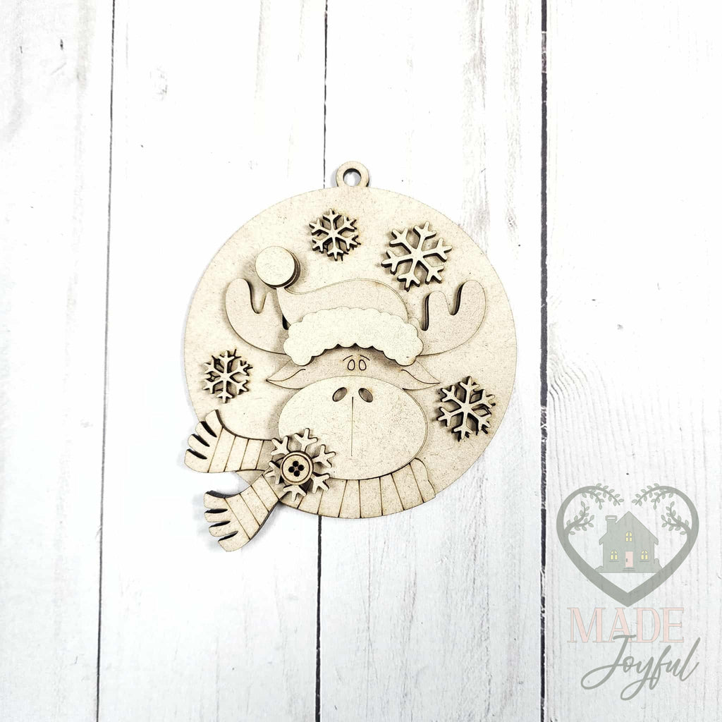 Unfinished laser-cut wood round moose ornament kit with snowflakes, ready to paint at a DIY party in Williamson County, TN.