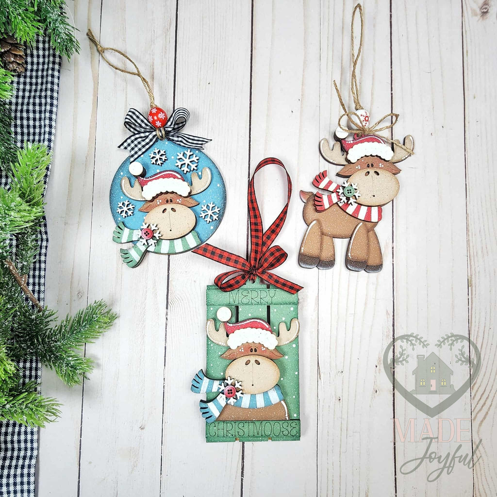 Christmoose ornament set with a round moose ornament, Merry Christmoose gift card holder and standing moose in a striped scarf, hand-painted in Brentwood, TN.