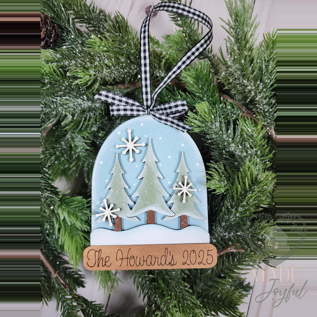 Snow globe ornament with pine trees and a personalized family name base, hand-painted in Brentwood, TN.