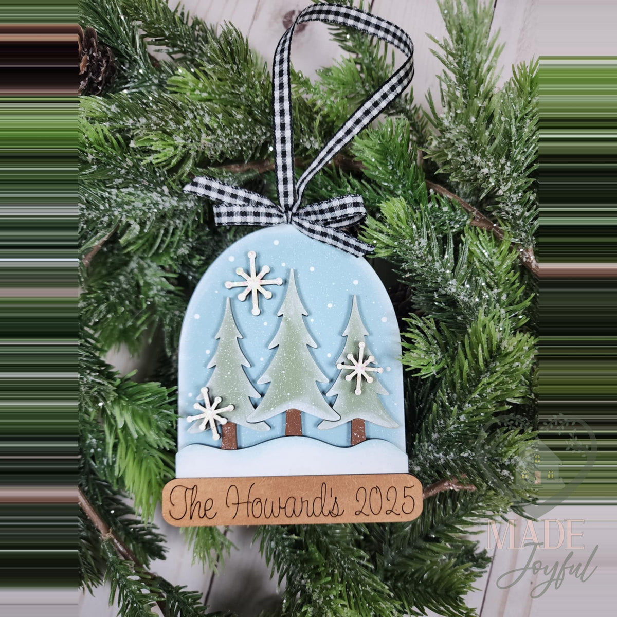 Snow globe ornament with pine trees and a personalized family name base, hand-painted in Brentwood, TN.