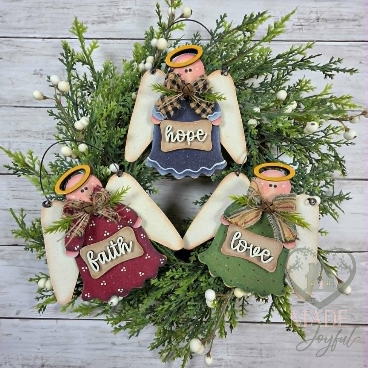 Three prim angel ornaments holding Faith, Hope and Love signs with homespun bows and halos, on a wreath, hand-painted in Brentwood, TN.