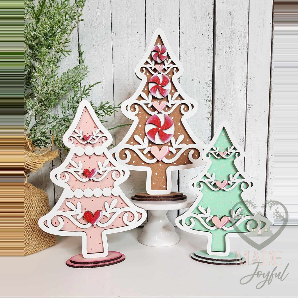 Three gingerbread Christmas tree shelf sitters in pink, brown, and mint with peppermints, hand-painted in Brentwood, TN.