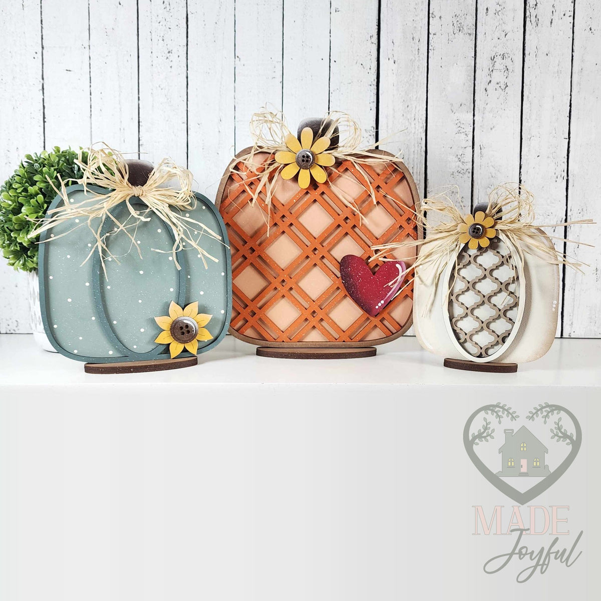Trio of harvest pumpkin shelf sitters in teal, orange lattice, and white with sunflowers, hand-painted in Brentwood, TN.