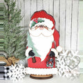 Woodland Santa in a red coat holding a tree and lantern, hand-painted in Brentwood, TN.