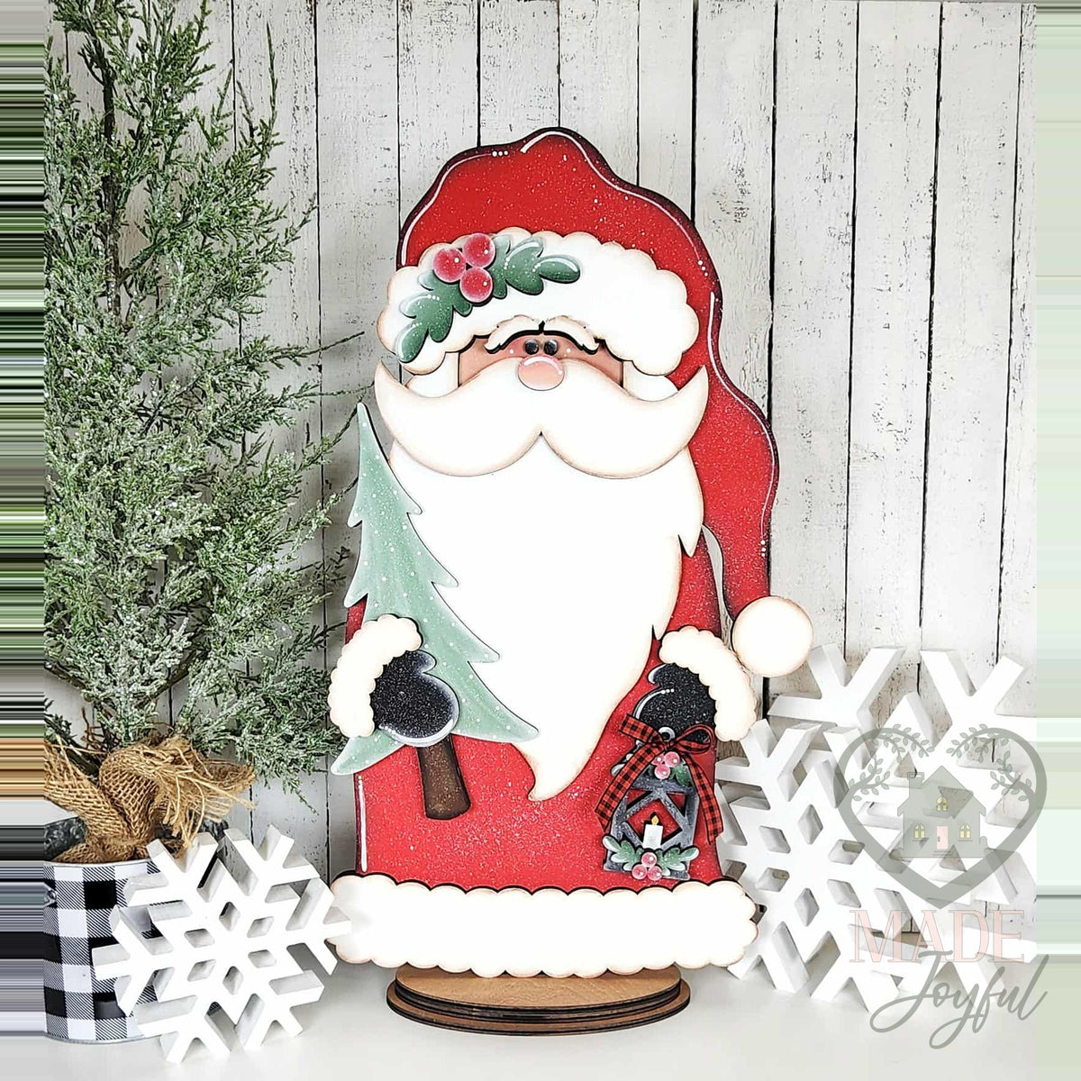 Woodland Santa in a red coat holding a tree and lantern, hand-painted in Brentwood, TN.