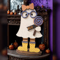 Gertie the Ghost shelf sitter with purple glasses, polka-dot orange bow, swirl lollipop, BOO tag, striped stockings, and yellow polka-dot boots on a Halloween mantel, hand-painted in Brentwood, TN.