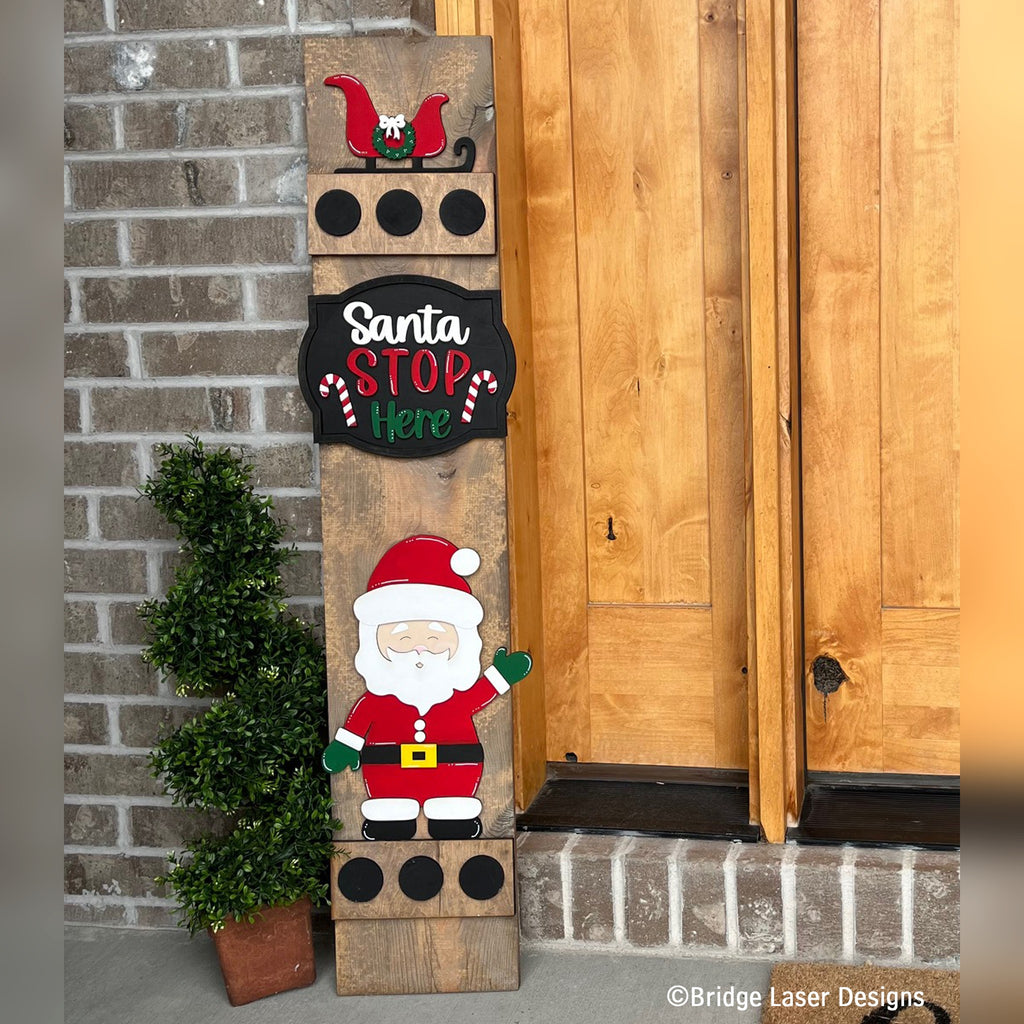 Santa Stop Here interchangeable porch leaner with a sleigh, a Santa Stop Here sign, and a waving Santa on a stained wood base by a front door