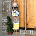 Hello Spring interchangeable porch leaner with a birdhouse, a Hello Spring sign, and a yellow rain boot full of flowers on a stained wood base