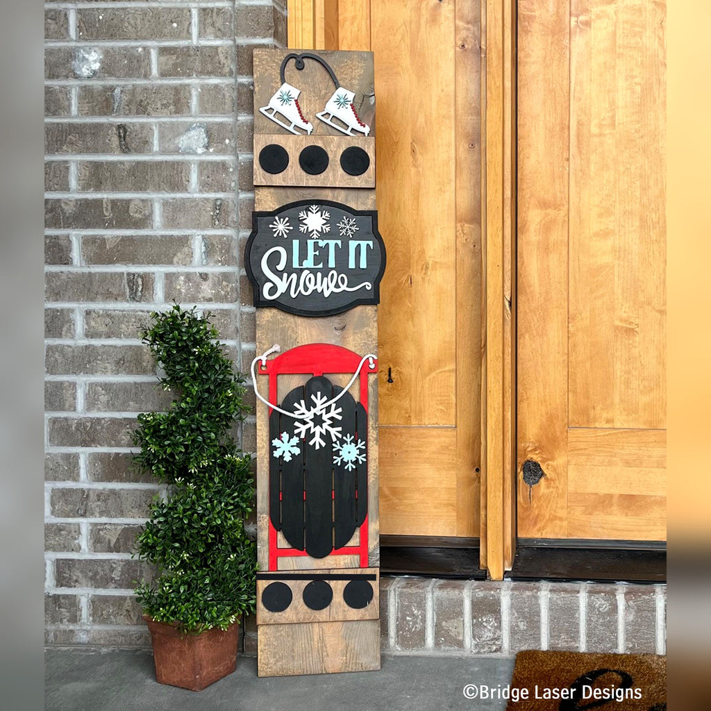 Let It Snow interchangeable porch leaner with ice skates, a Let It Snow sign, and a vintage red sled with a snowflake on a stained wood base