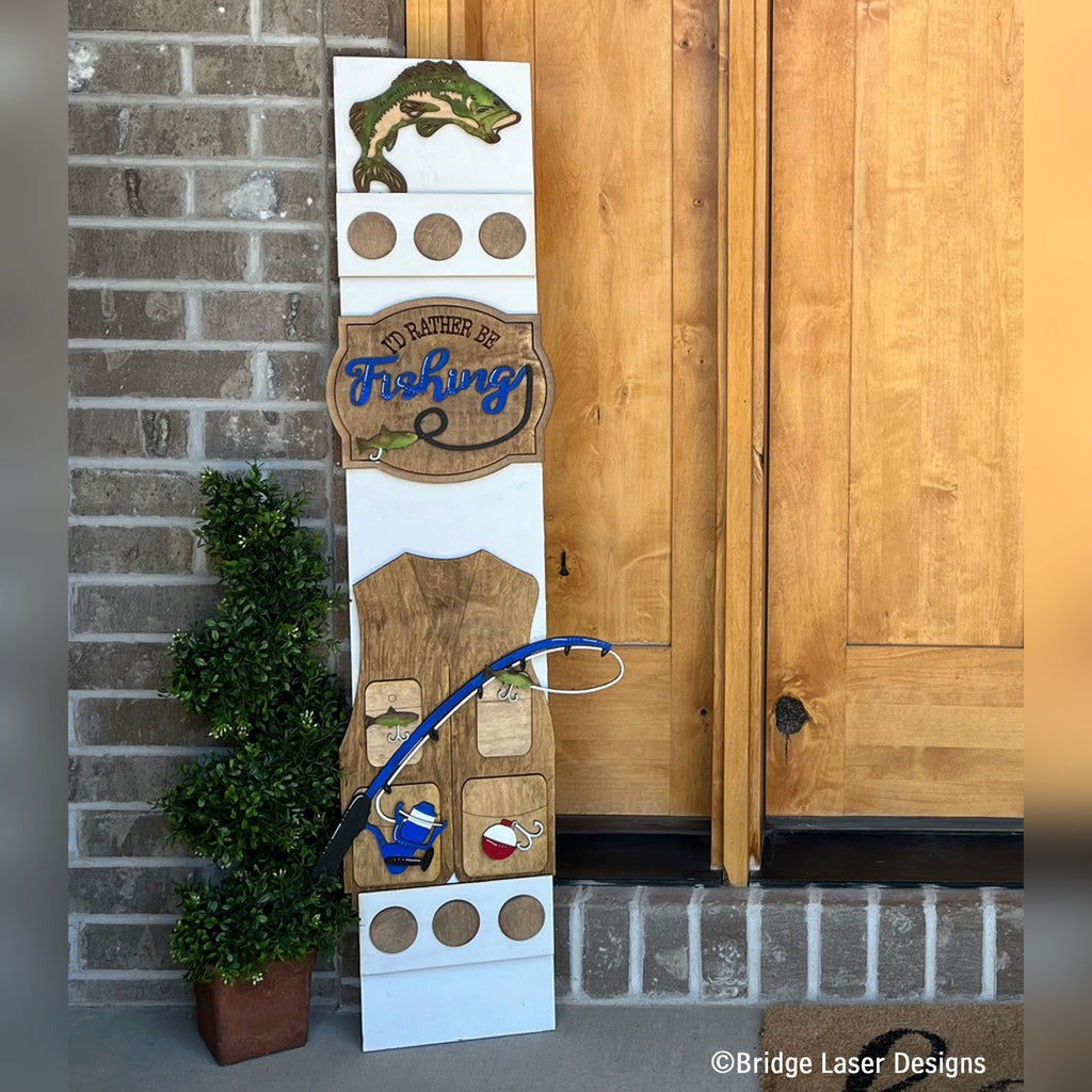 Fishing interchangeable porch leaner with a bass fish, a Fishing sign, and a fishing vest with a rod on a white wood base by a front door