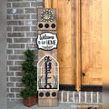 Oh Hello interchangeable porch leaner with a boxwood wreath, a Welcome to Our Home sign, and an arched Oh Hello sign on a stained wood base
