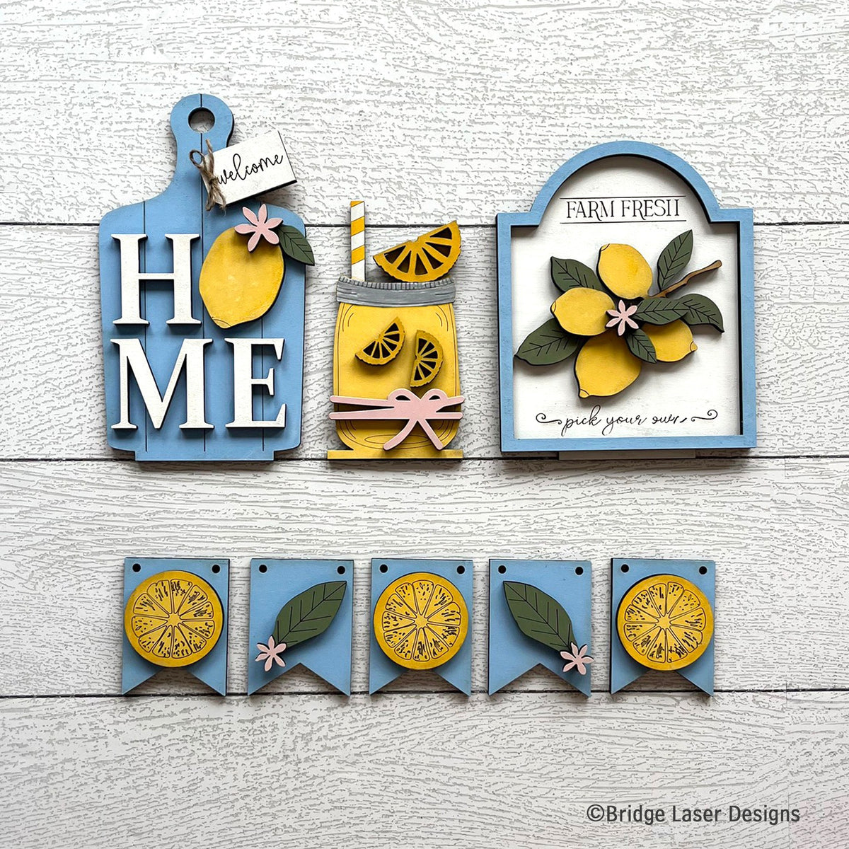 Lemon interchangeable bench decor set with a HOME sign, a lemonade pitcher, a Farm Fresh lemons sign, and a lemon slice banner