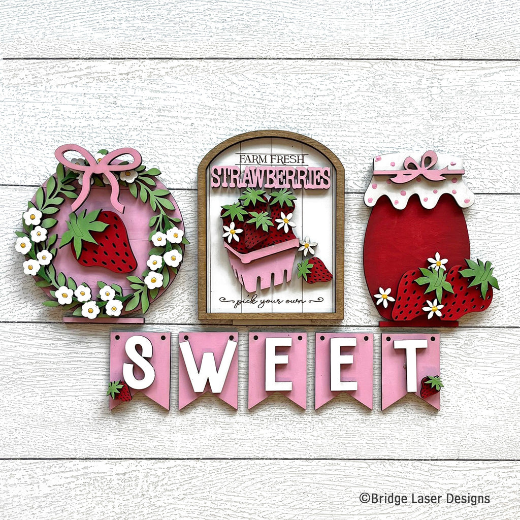 Strawberry interchangeable bench decor set with a strawberry wreath, a Farm Fresh Strawberries sign, a jam jar, and a pink SWEET banner