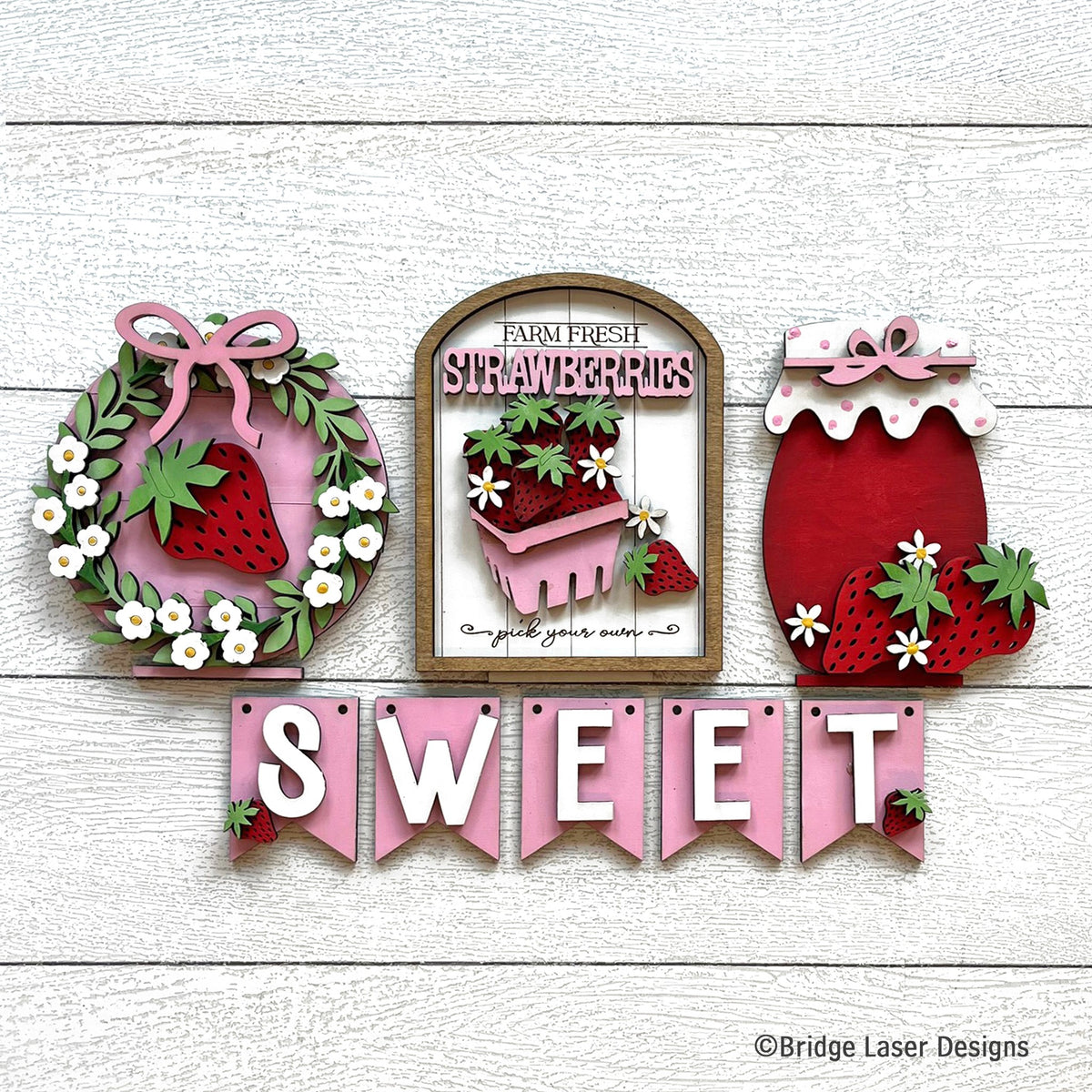 Strawberry interchangeable bench decor set with a strawberry wreath, a Farm Fresh Strawberries sign, a jam jar, and a pink SWEET banner