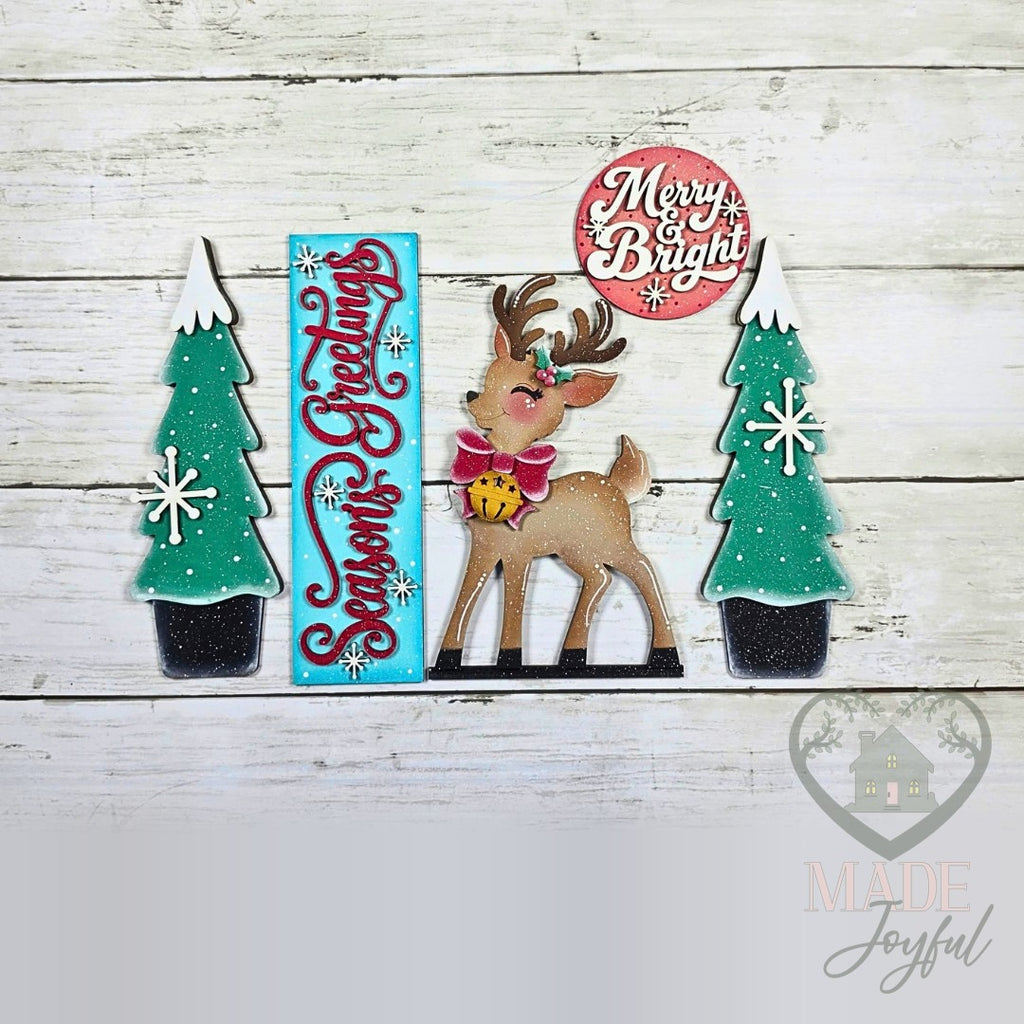 Retro Christmas porch set pieces laid out: Season's Greetings sign, flocked trees, reindeer, and Merry & Bright round, hand-painted in Brentwood, TN.