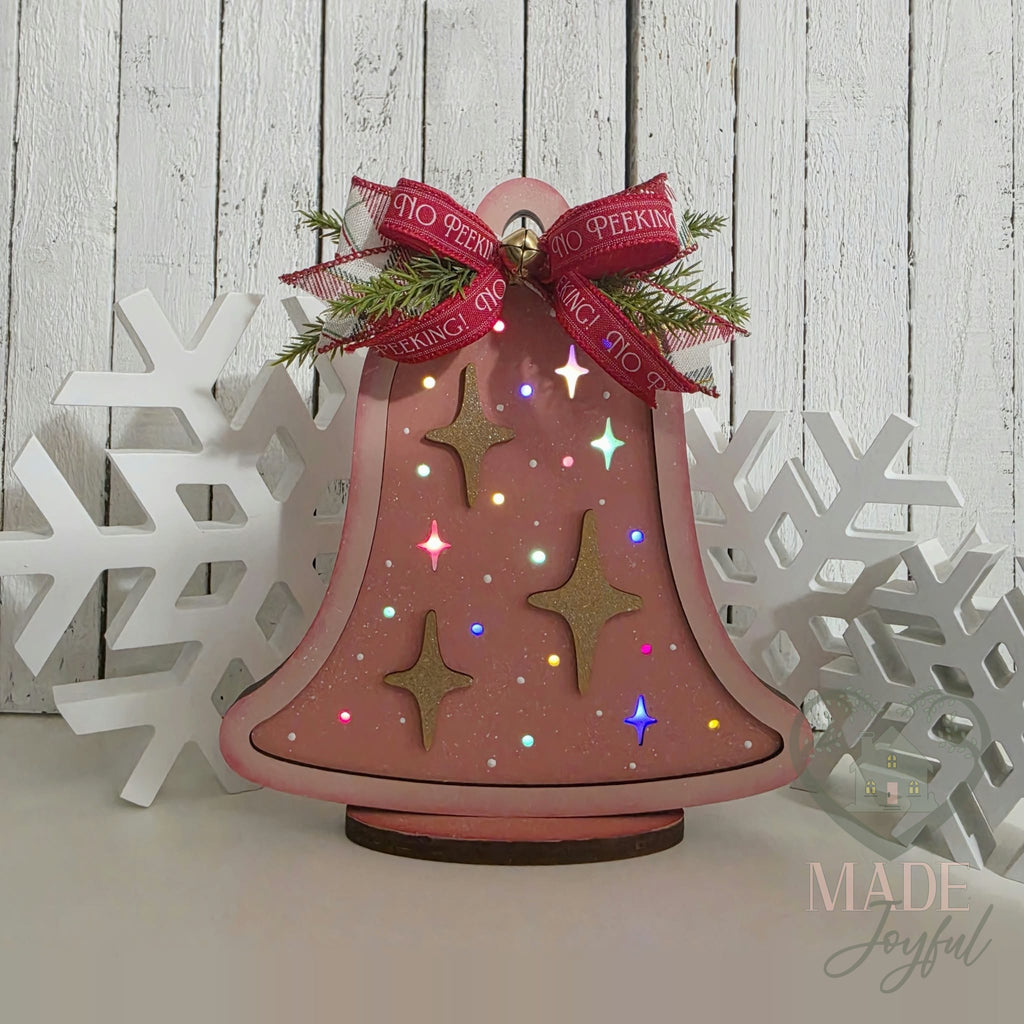 Retro Christmas bell glowing with colored lights shining through the star cutouts, hand-painted in Brentwood, TN.