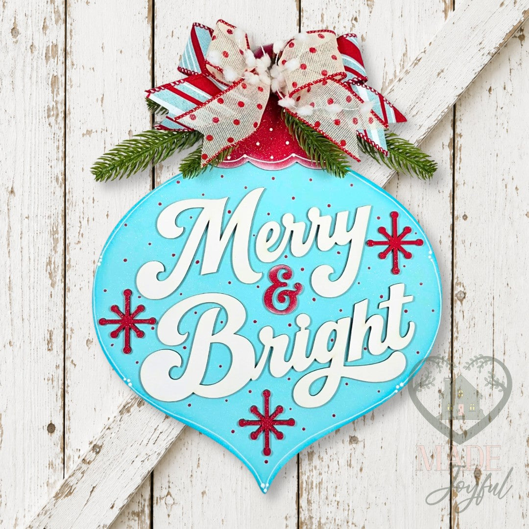 Aqua vintage bulb door hanger with Merry & Bright script, red starbursts, and a red and white bow, hand-painted in Brentwood, TN.