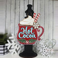 Red Hot Cocoa mug door hanger with whipped cream, peppermint sticks, snowflake, and holly displayed on a black post, hand-painted in Brentwood, TN.