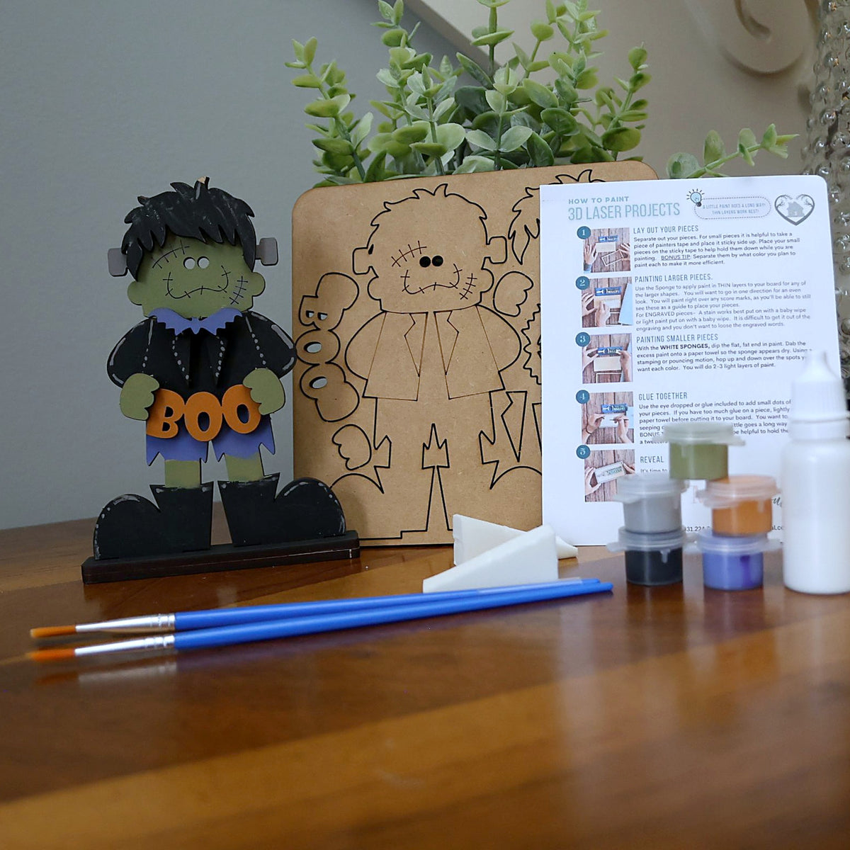 Kids DIY paint kit: Frankie holding a BOO sign, with wood pieces, paints, brushes, sponges, glue and instructions. A favorite at kids' DIY parties in Williamson County, TN